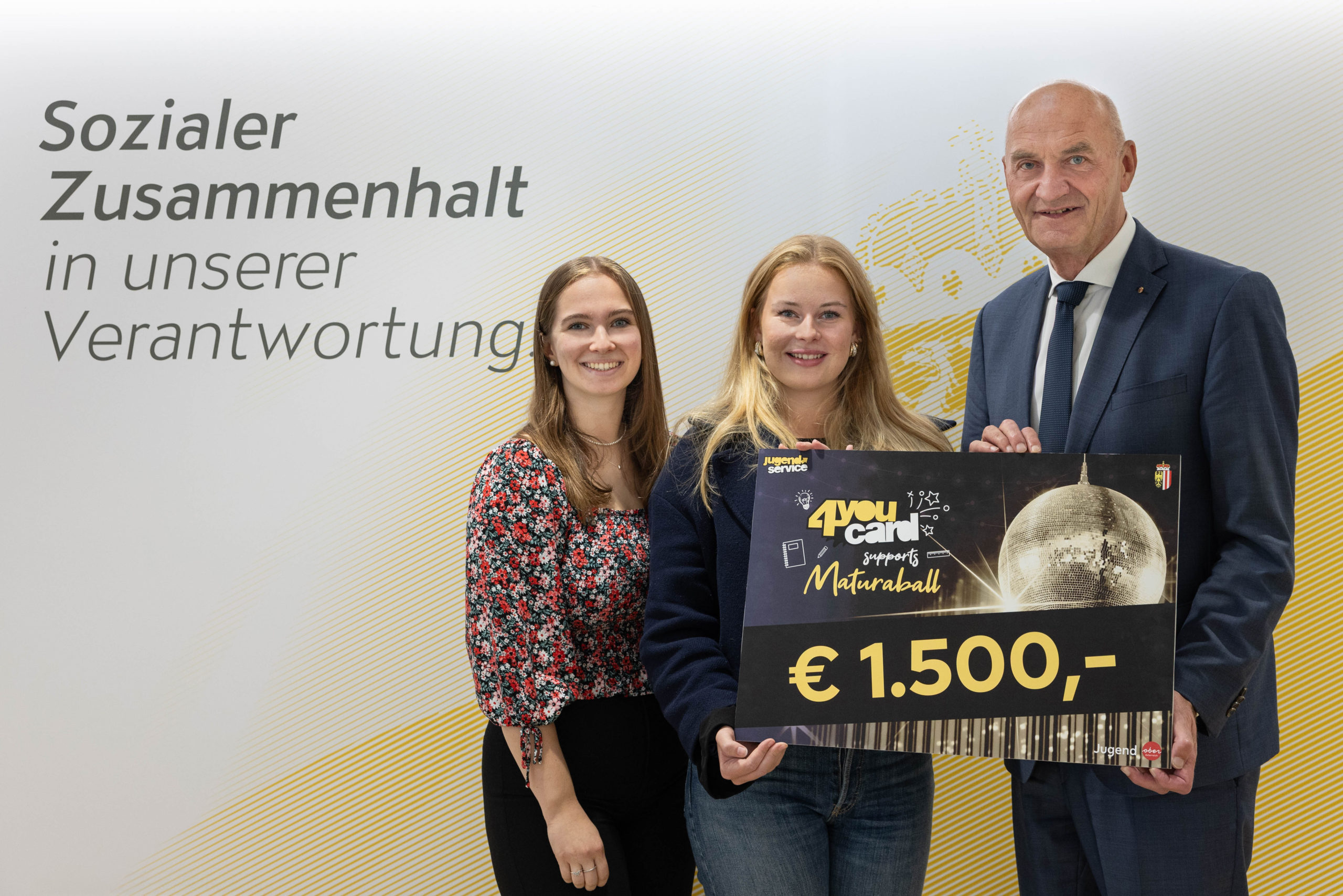 Foto (Land OÖ/Spenlingwimmer): Übergabe des Hauptpreises: Jugend-Landesrat Christian Dörfel überreicht den Hauptgewinn an die Ballleitung der HAK Wels Anna Raxendorfer und Lena Atzlesberger.
