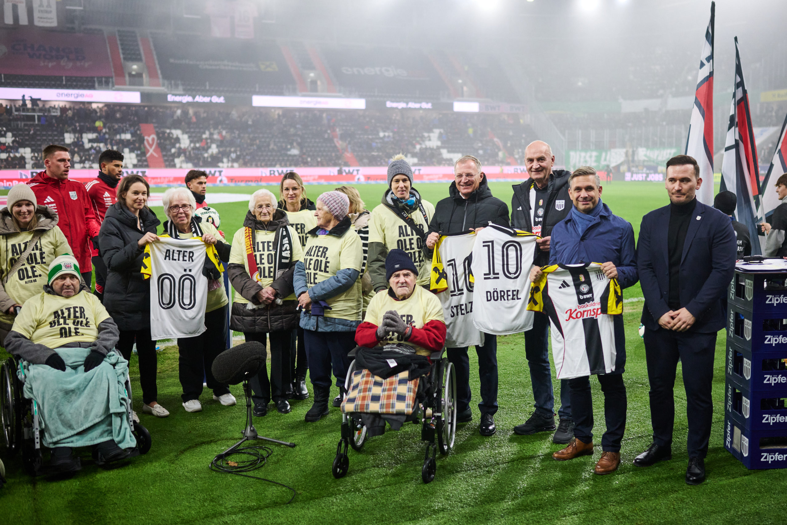 Landeshauptmann Mag. Thomas Stelzer (4.v.r.), Wirtschaftsminister Dr. Wolfgang Hattmannsdorfer (2.v.r.), Sozial-Landesrat Dr. Christian Dörfel (3.v.r.), LASK Geschäftsführer Mag. Mergim Bresilla (1.v.r.) und ALTER OÖ-Geschäftsführerin Anna Ferihumer (5.v.l.) mit älteren Menschen und Pflegekräften vor dem Spitzenspiel LASK gegen Rapid. Foto: Land OÖ/Peter Mayr